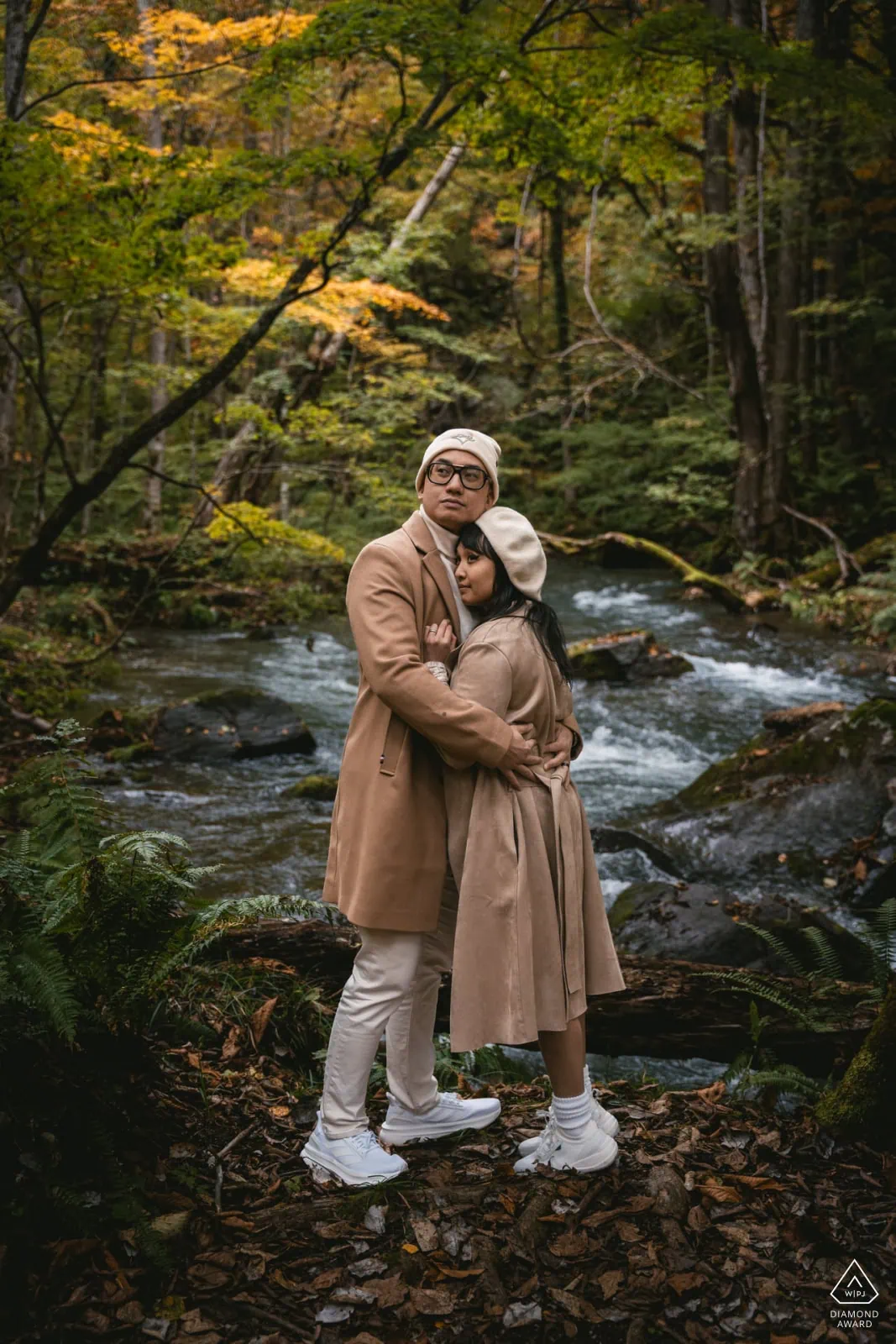Romantic couple embracing in a forest stream during fall, perfect for elopement photography.