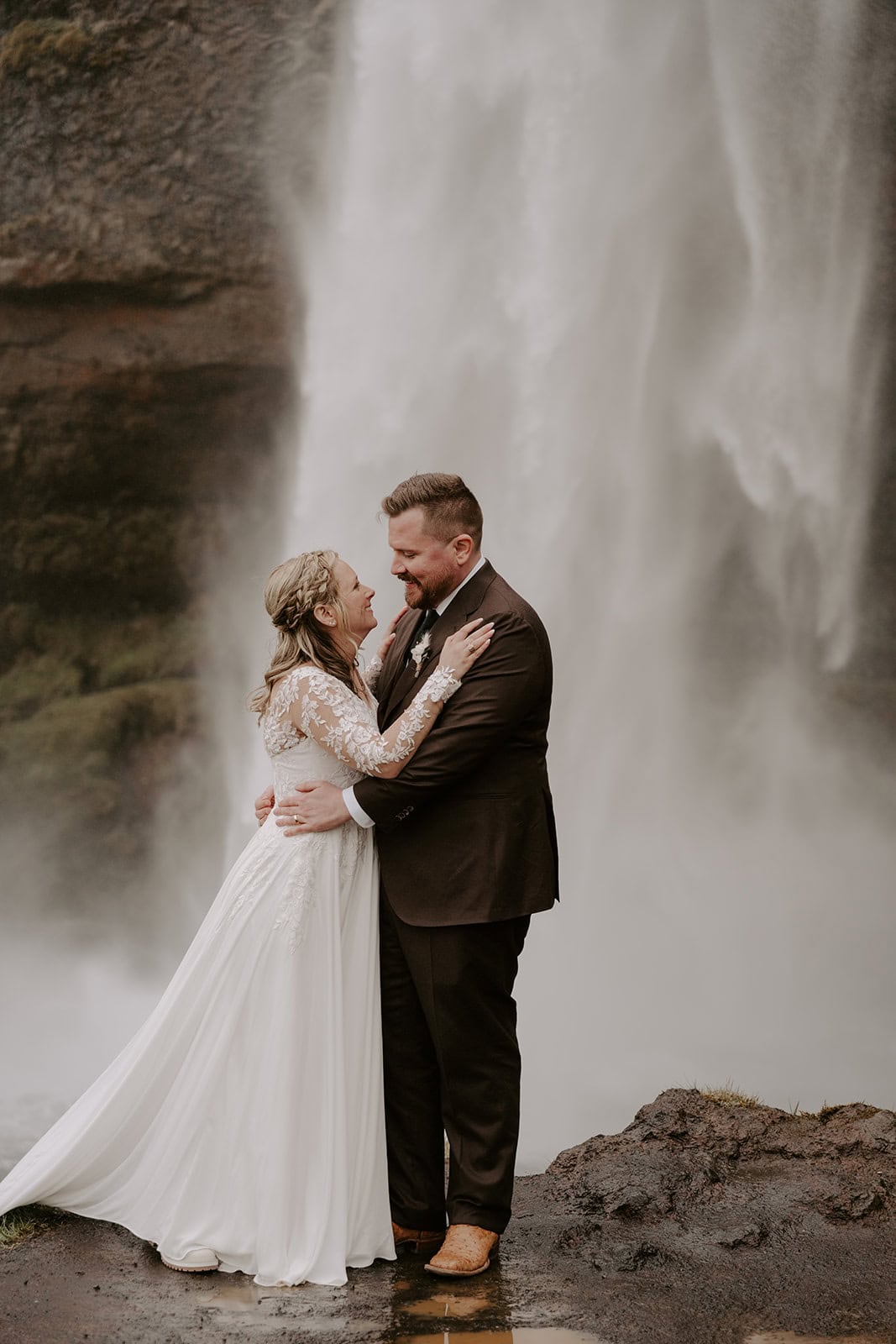 Couple standing by a cascading waterfall during their Iceland waterfall elopement