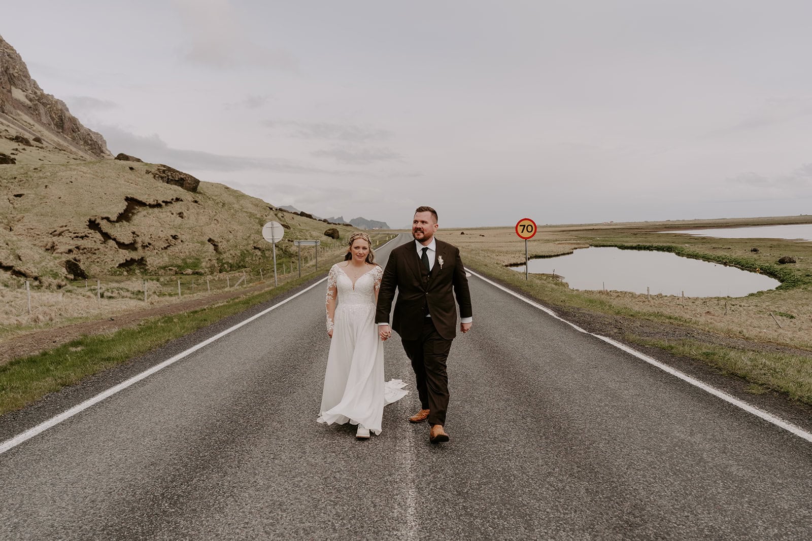 The couple walking hand in hand at their Iceland waterfall elopement