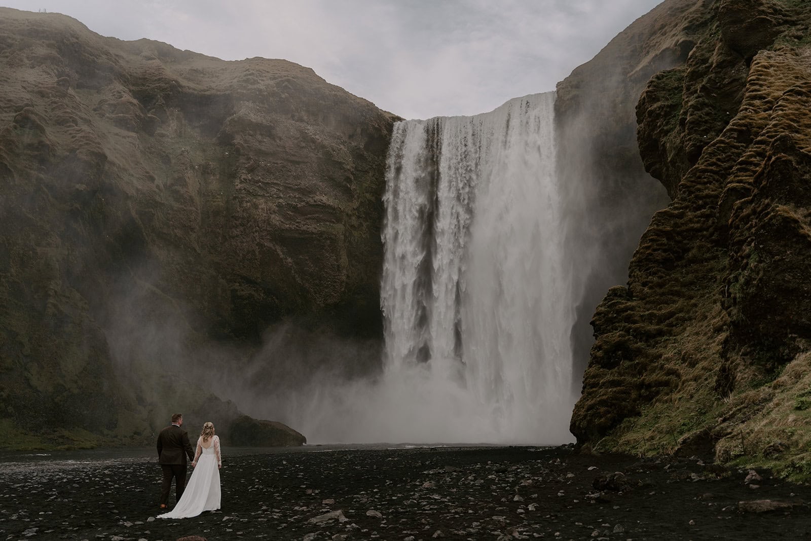 Iceland waterfall elopement with mist rising from the waterfall in the background
