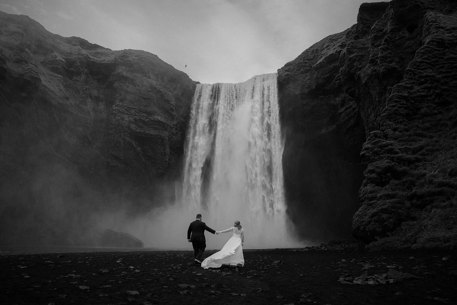 Dramatic view of the couple by the waterfall during their Iceland waterfall elopement