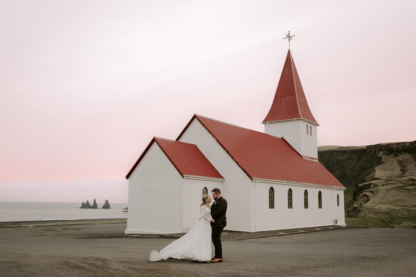 The couple sharing a joyful moment by a church during their Iceland elopement