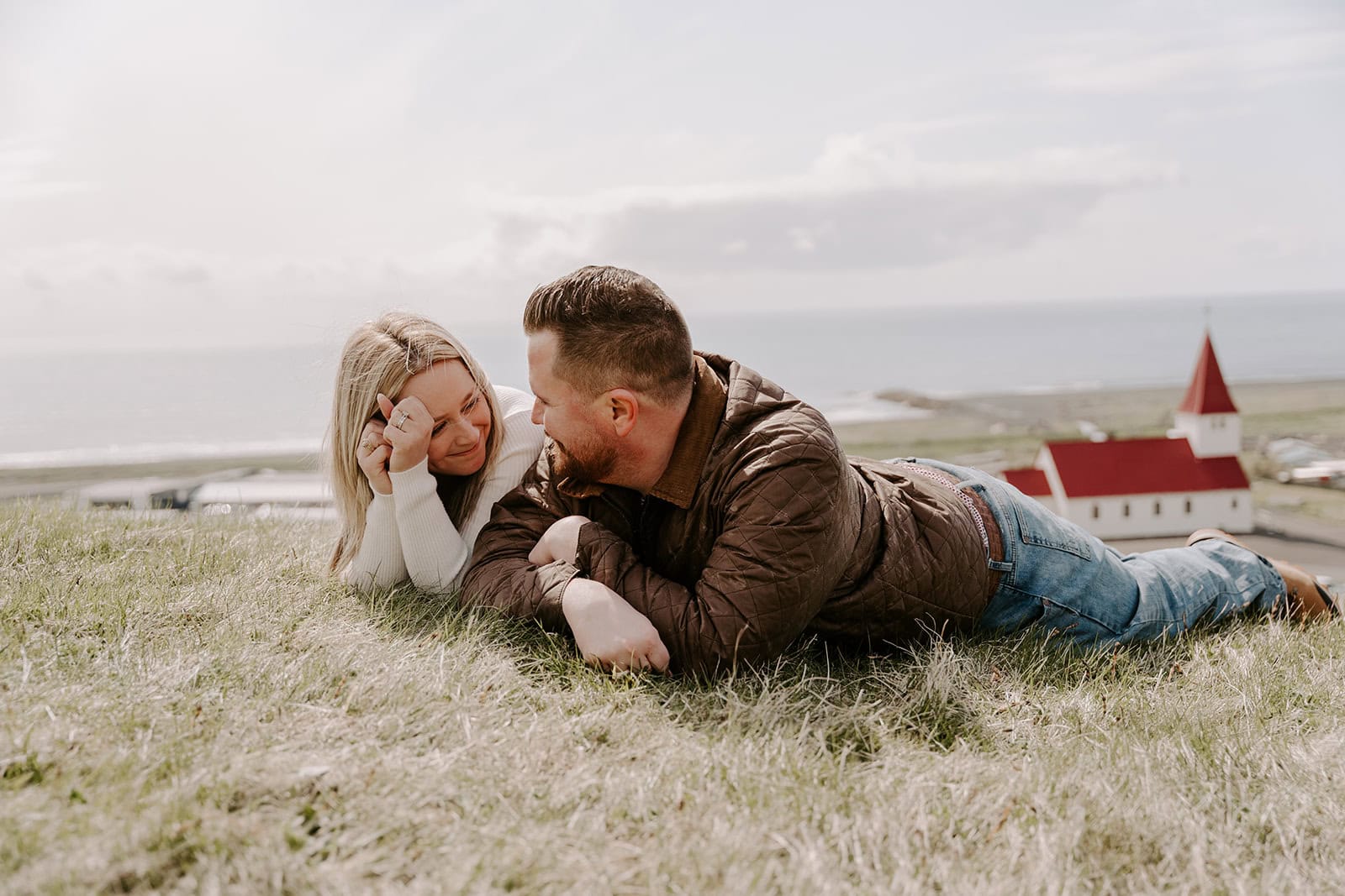 The couple landing in a mossy field near the waterfall during their Iceland elopement