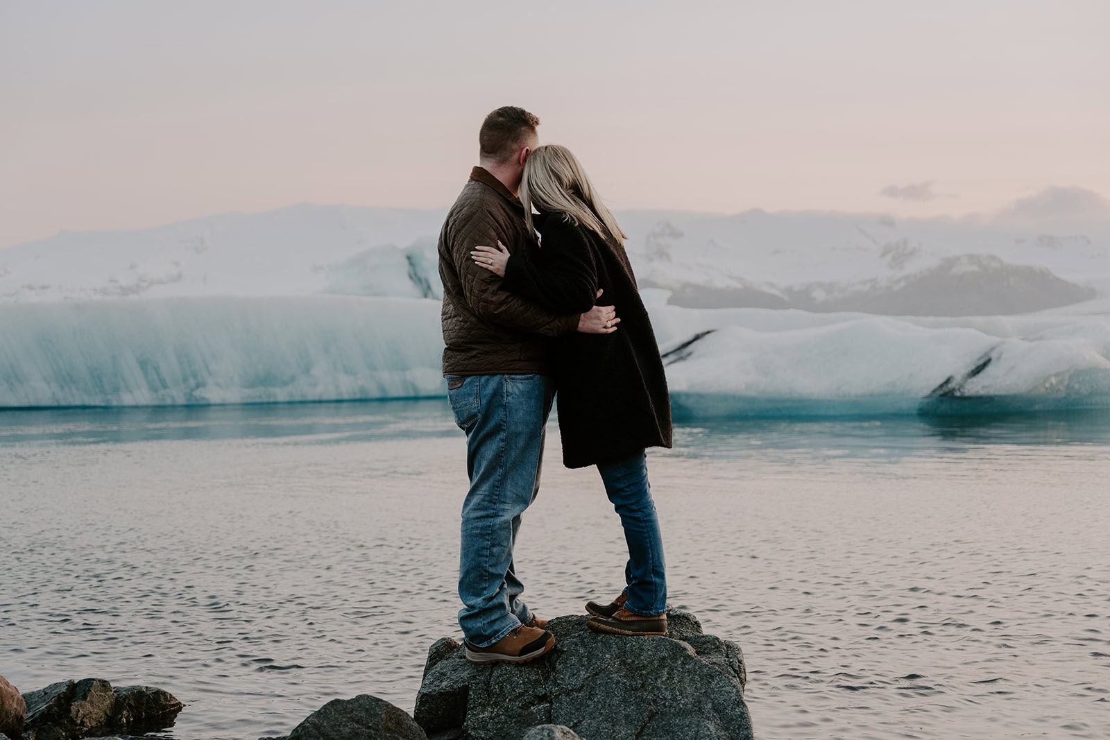 Couple posing on a rocky ledge by the galcier during their Iceland elopement