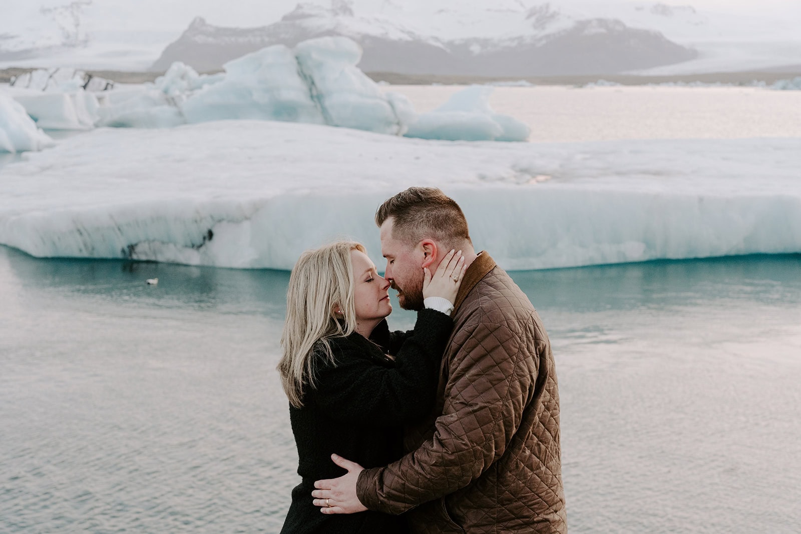 A romantic kiss in front of a glacier during an Iceland adventure elopement