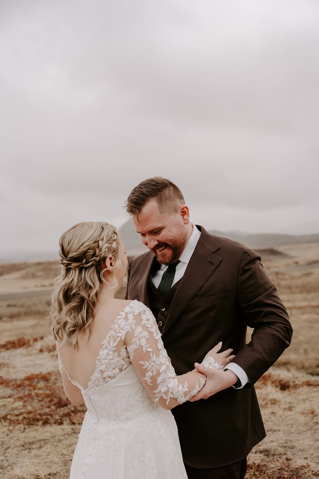 A beautiful shot of the groom discovering his bride's dress for the first time, during their Iceland waterfall elopement