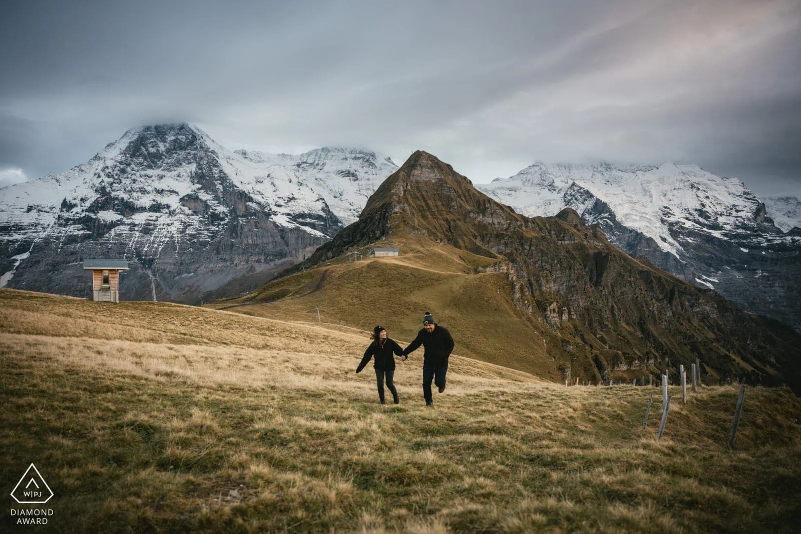 Elopement couple holding hands in scenic mountain landscape with snow-capped peaks in the background.