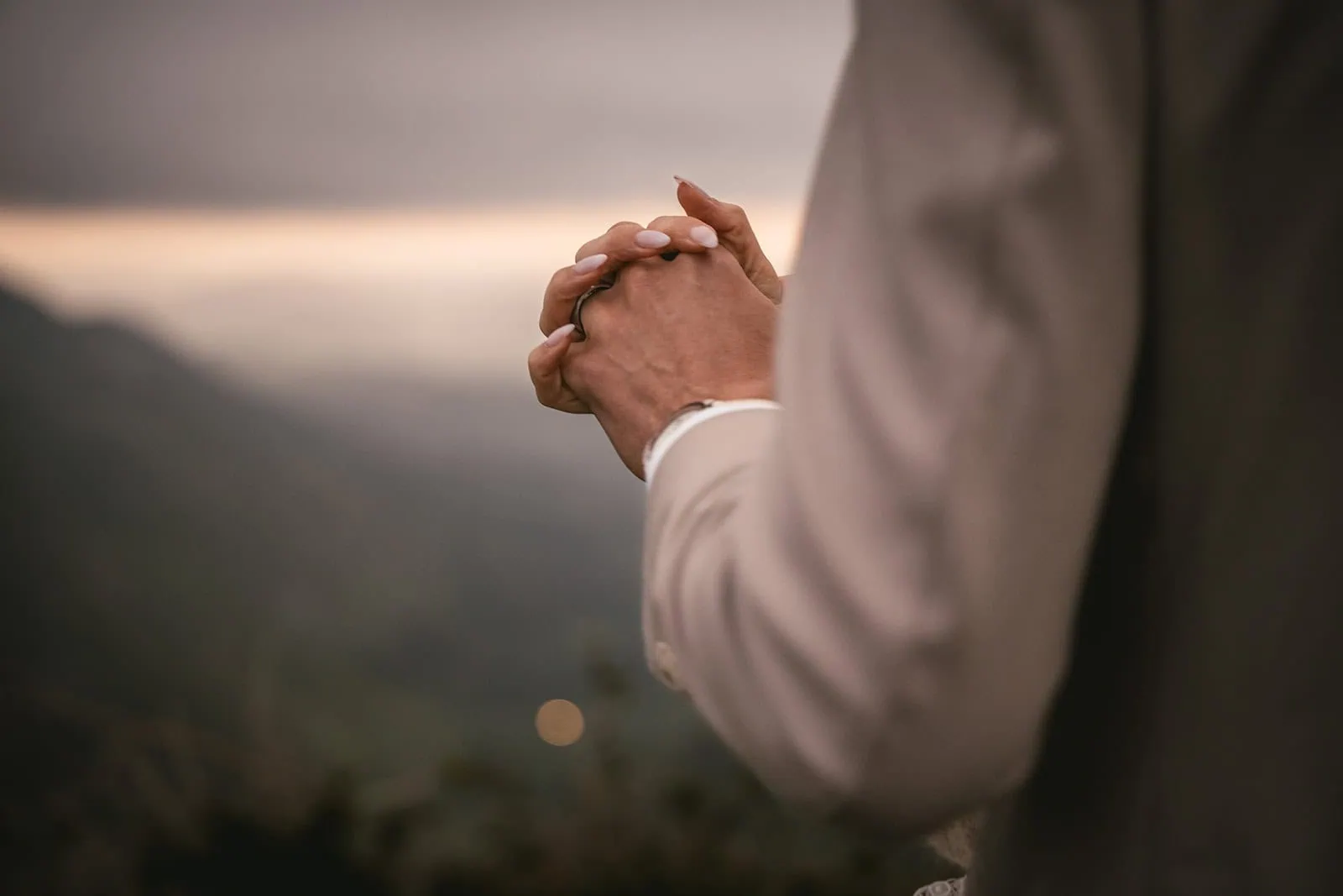 Close-up of couple’s hands with Asturias mountains in the distance