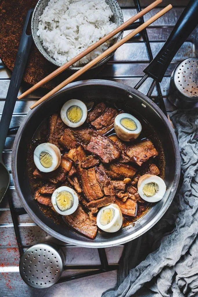 A mouthwatering Filipino adobo dish with pork, eggs, and rice, captured in a warm still life photo.
