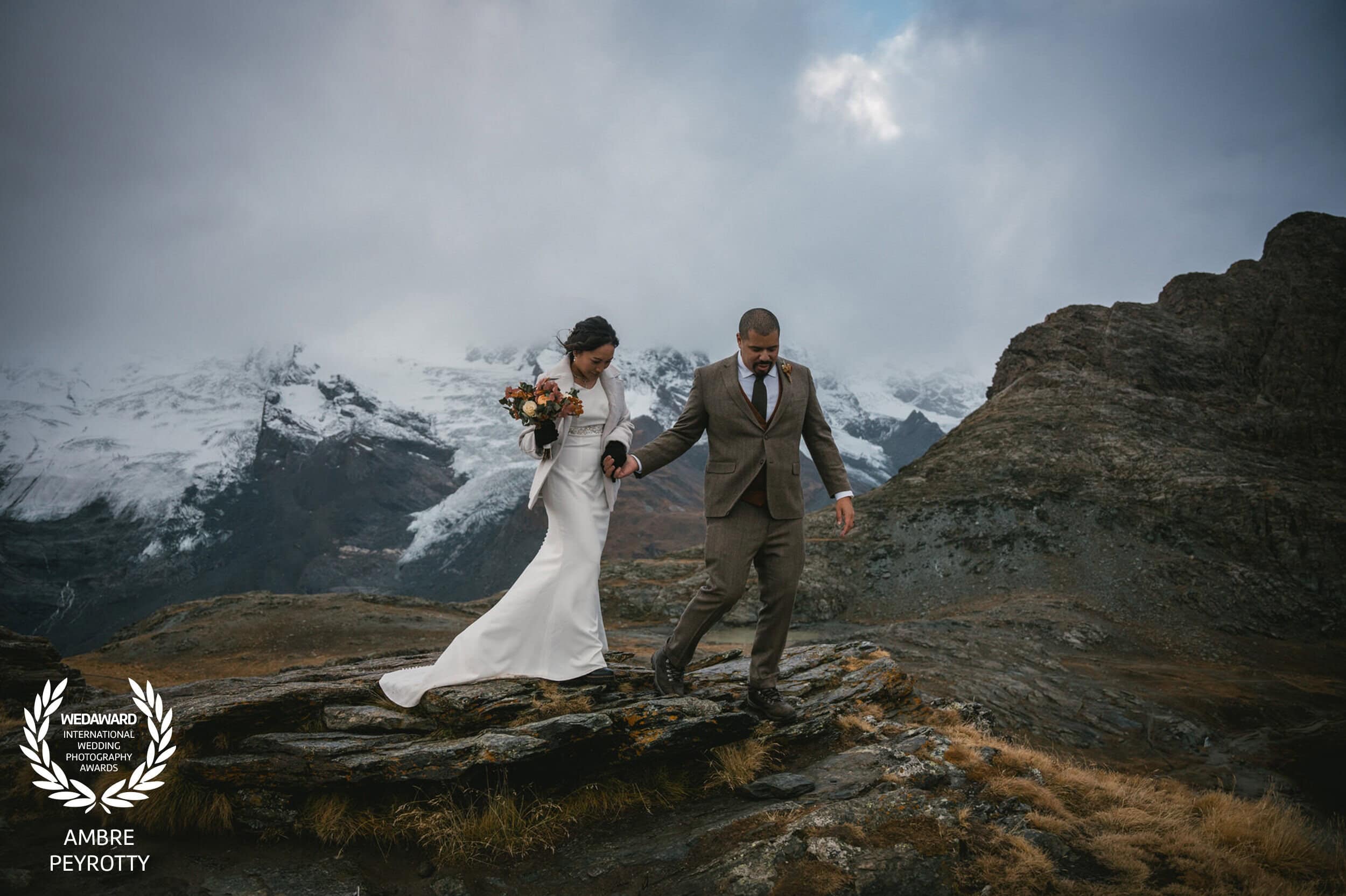 Adventure-seeking couple descending rocky mountain path, demonstrating the epic journeys included in our New Zealand elopement packages