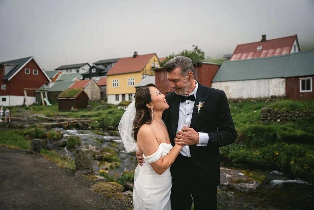 Portrait of the newlyweds in their Torshavn elopement, with a typical Faroese village as backdrop