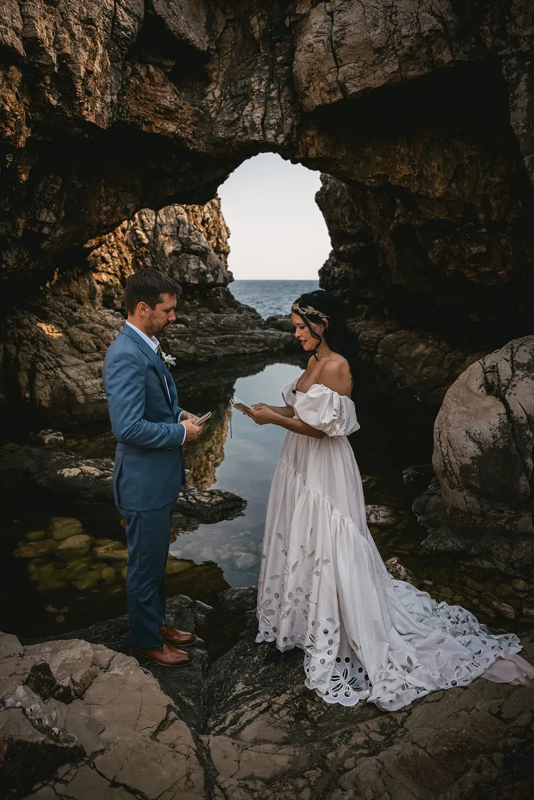 The couple framed by cave shadows and sparkling sea during their Dubrovnik elopement