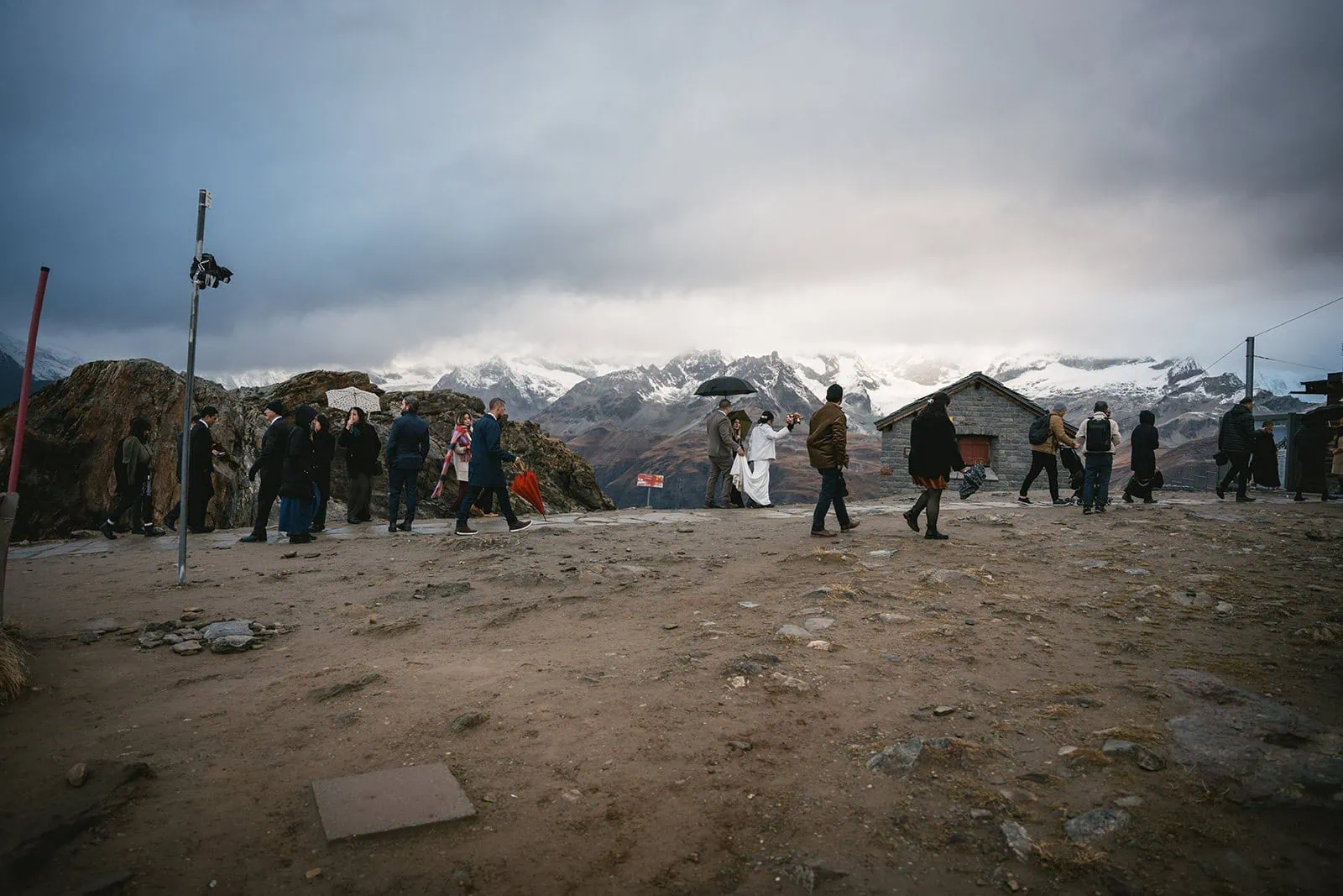 Newlyweds and their guests walk along the snowy path as they leave their Gornergrat elopement ceremony spot