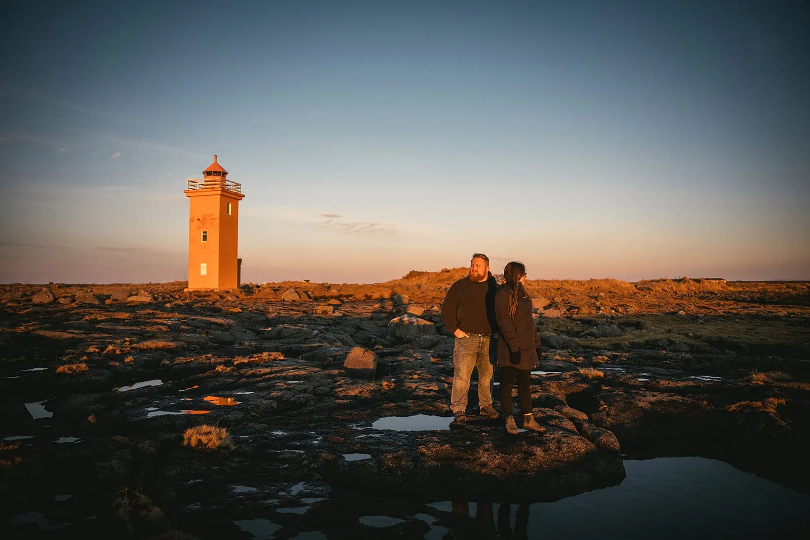 Newlyweds exploring around an epic lighthouse during their Vik elopement