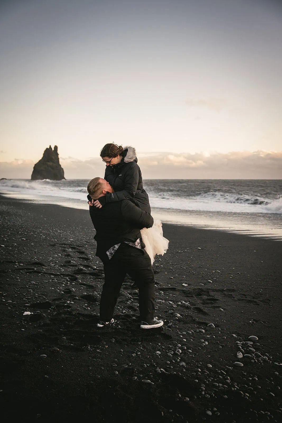 Holding each other close with basalt cliffs in the background during their Vik elopement
