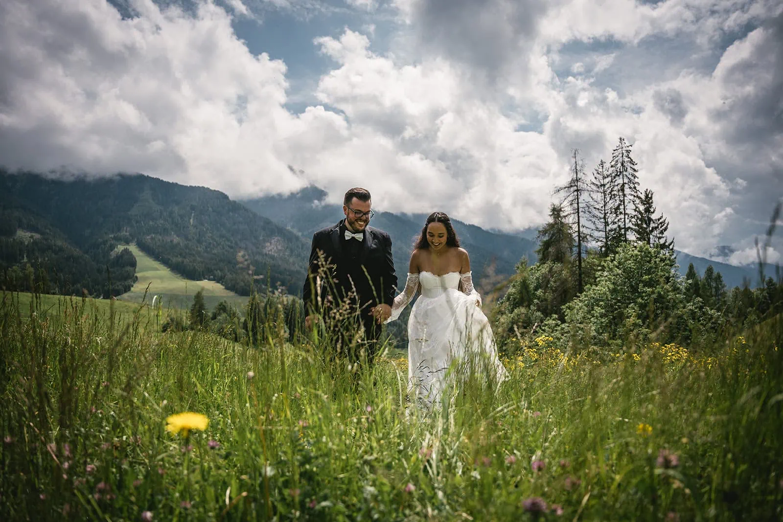 Walking hand by hand in a secluded field in their Dolomites elopement