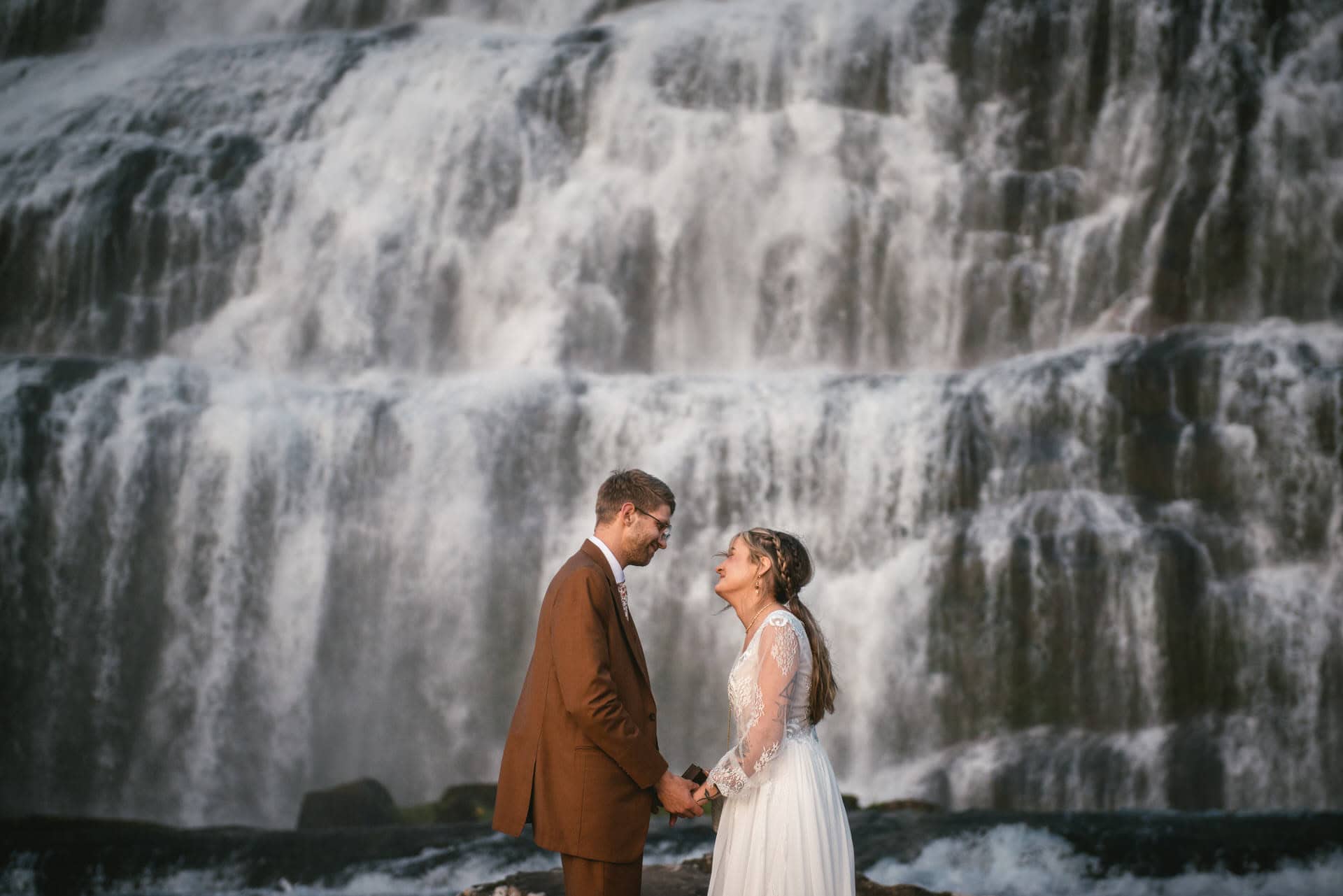 Couple eloping beside a powerful Icelandic waterfall