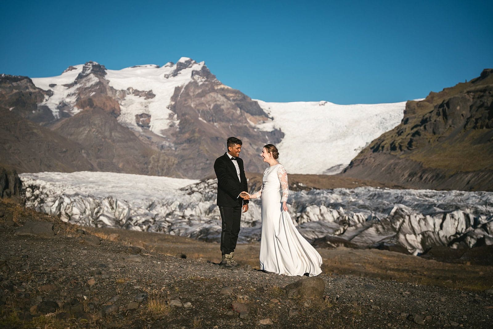 Couple glacier hiking among blue ice formations during their Iceland elopement