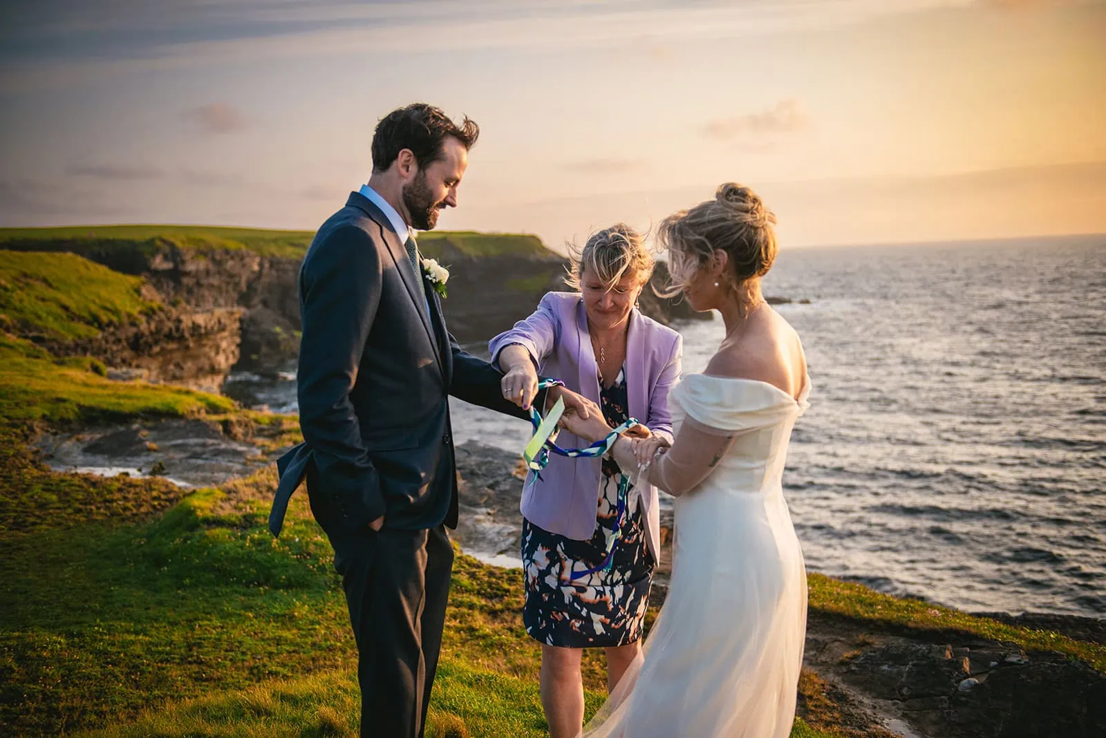The officiant tying the bride and groom's hands during their Ireland elopement ceremony