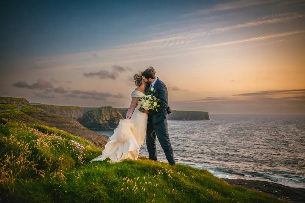 Tender embrace at sunset on cliffs, the ocean witnessed their Ireland elopement
