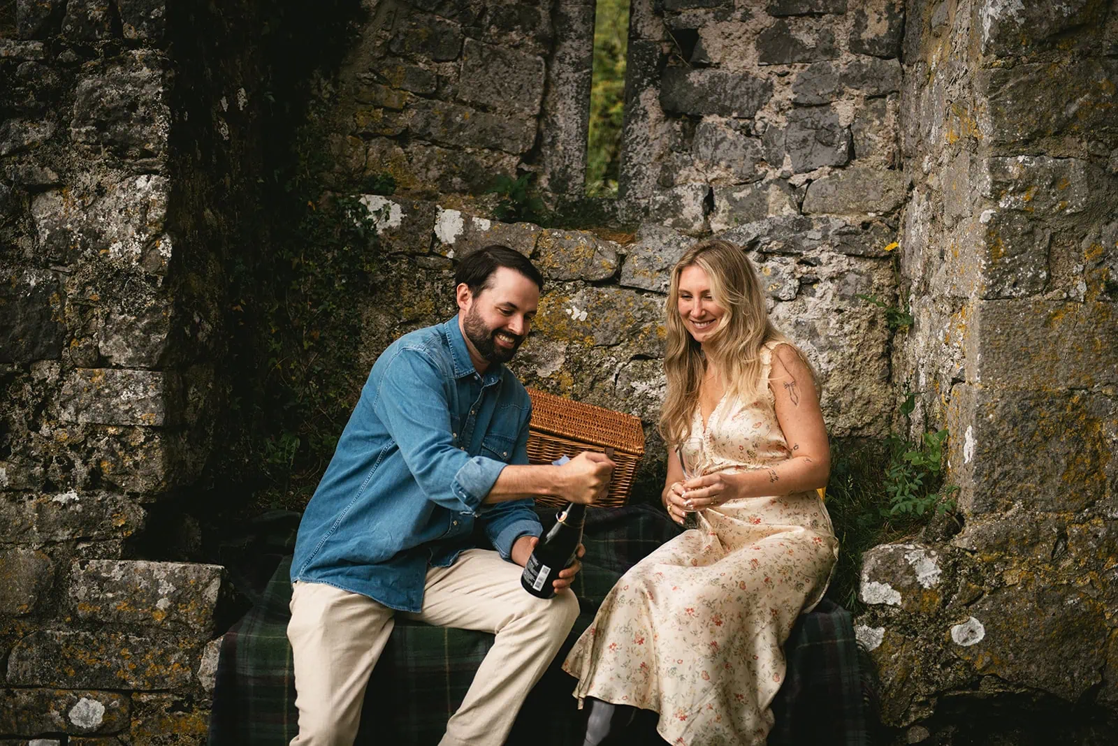 Popping champagne to celebrate their Ireland elopement during a picnic