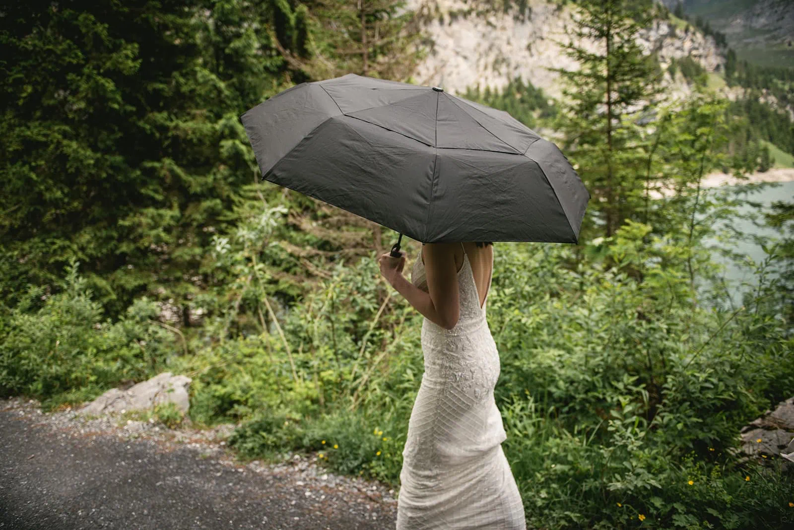 Bride holding an umbrella as she walks towards her Oeschinensee elopement ceremony site