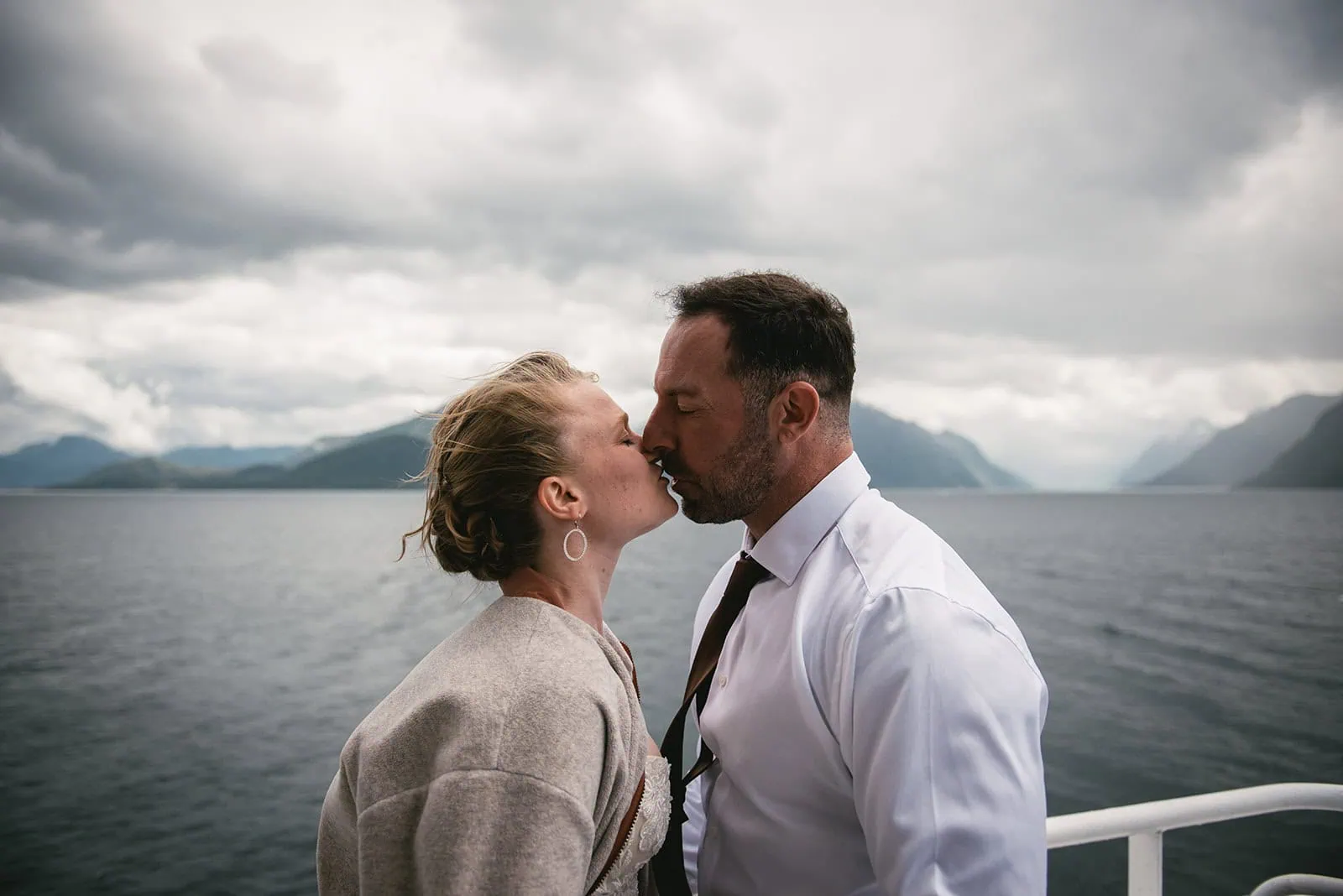 A kiss in the wind on the boat, as they begin their fjords elopement adventure
