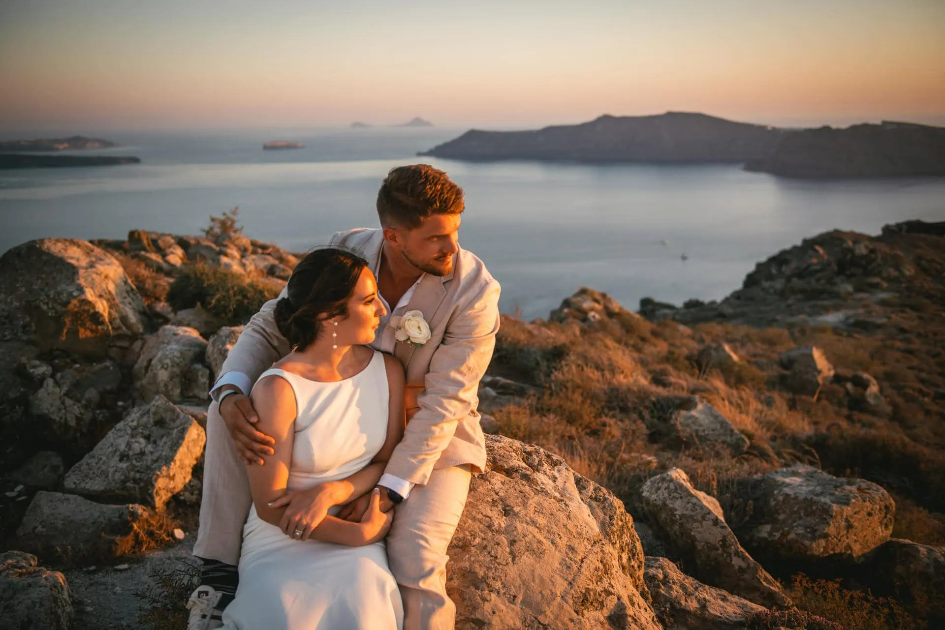 Romantic elopement photo capturing intimate moment during sunset with stunning caldera views.