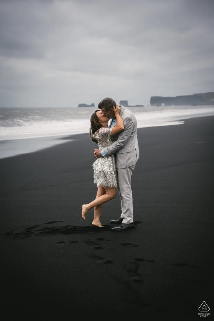 Romantic couple embracing on Iceland's black sand beach during elopement.