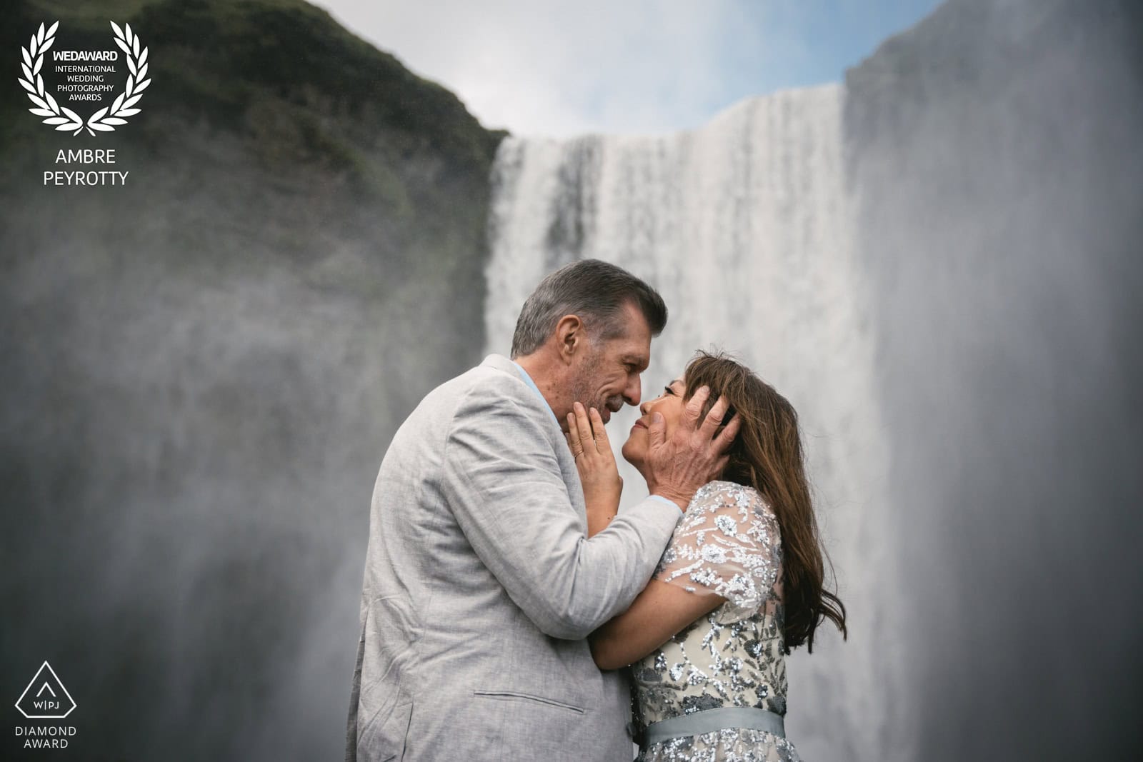 Elopement couple embracing with waterfall backdrop in Iceland.