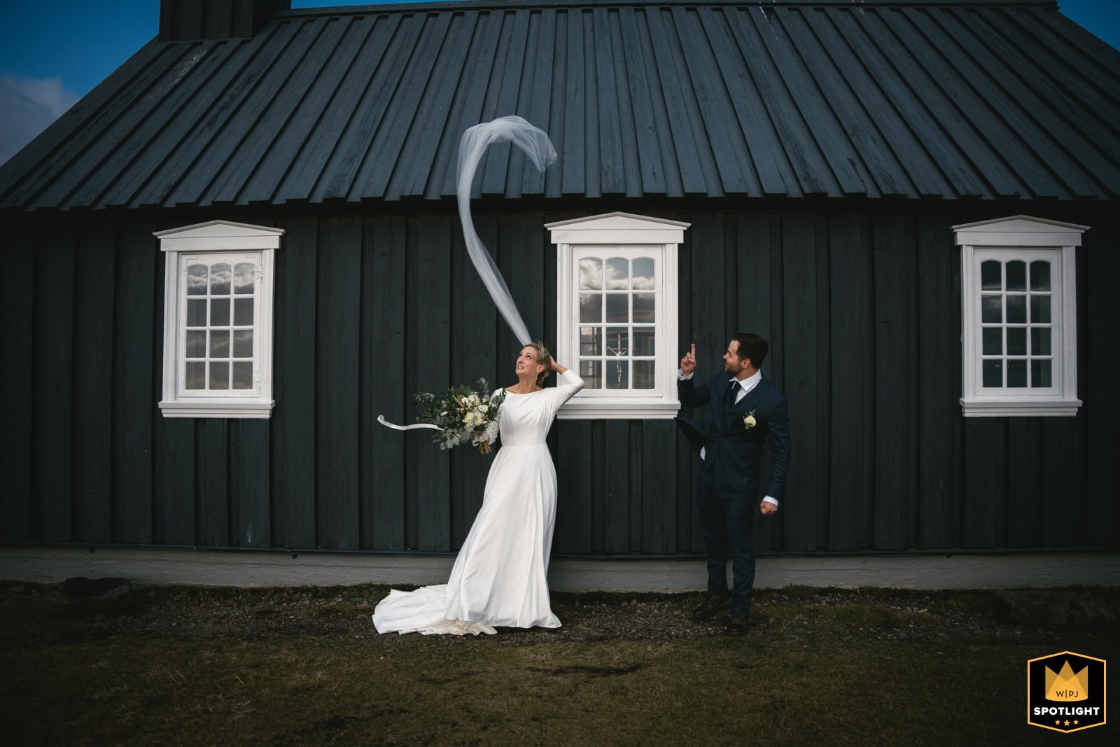 Elegant Icelandic elopement ceremony with bride and groom in front of a black wooden house.