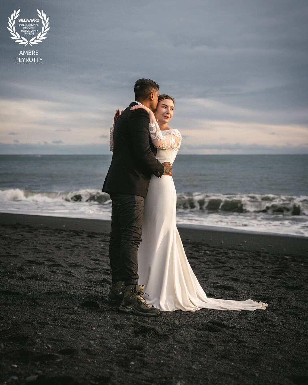 Romantic couple in wedding attire on Iceland's black sand beach during elopement.