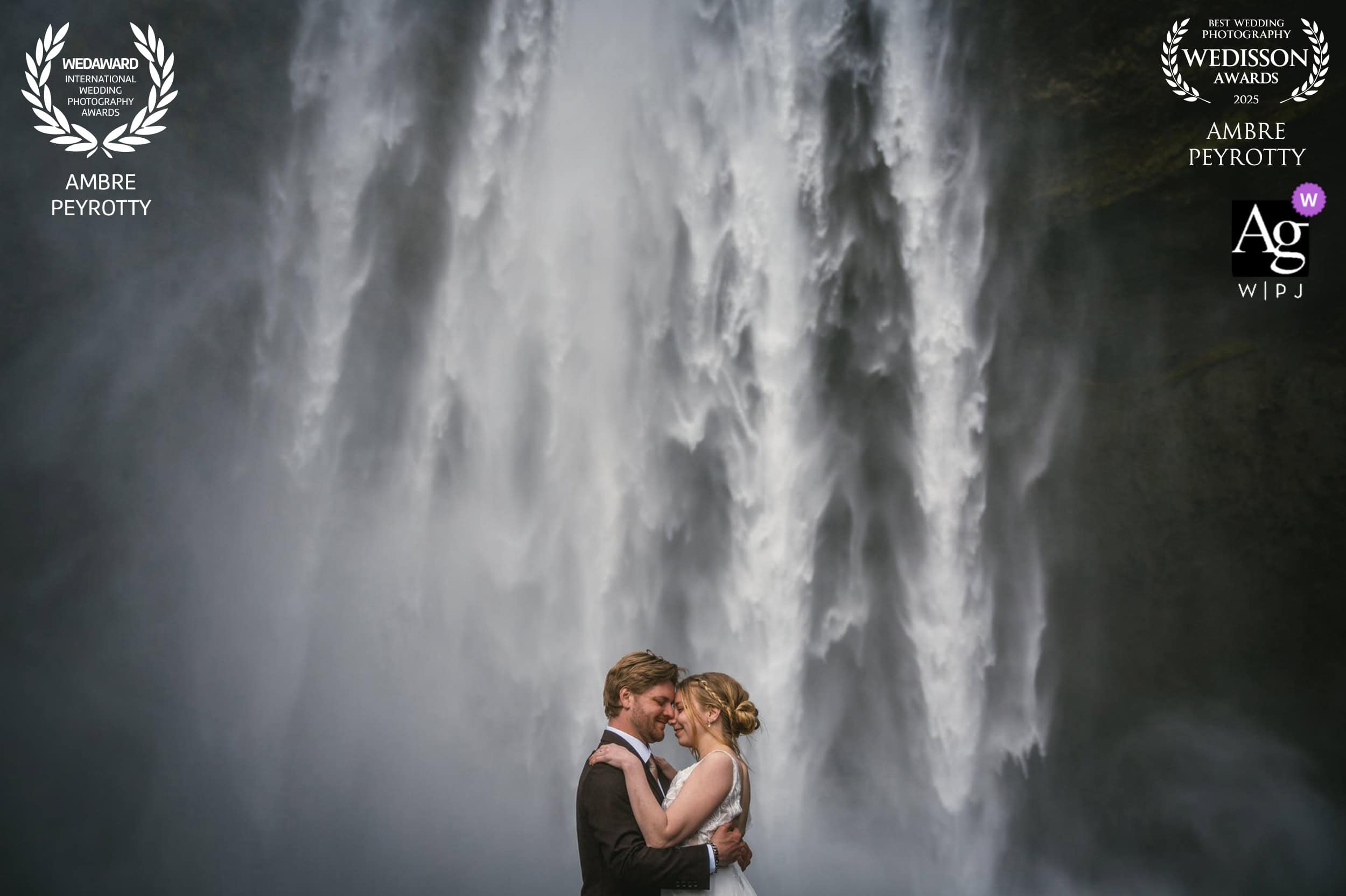 Elopement couple embracing beneath a stunning waterfall in Iceland, capturing love and adventure for.