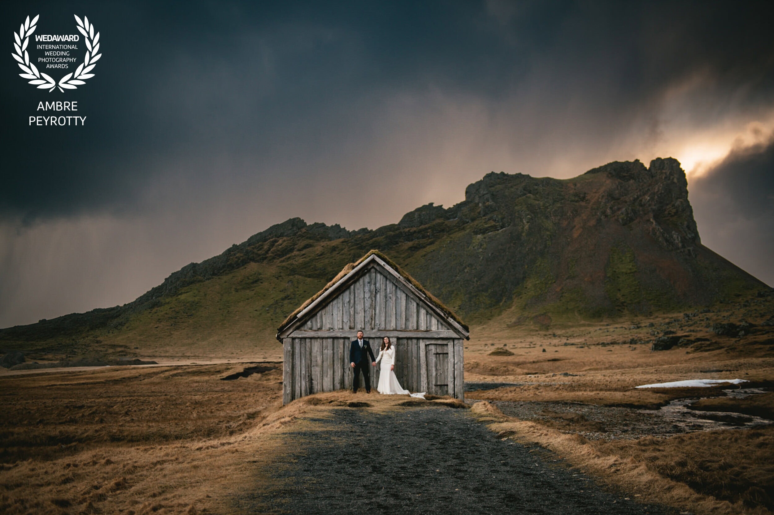 Wedding couple at a rustic wooden chapel in Iceland's dramatic landscape.