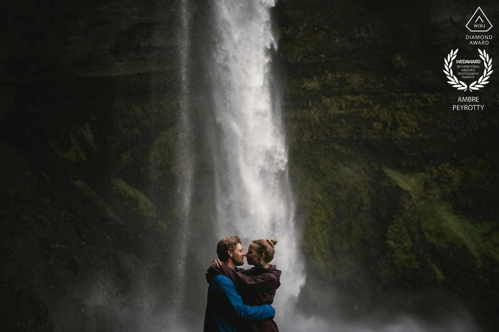 Intimate couple embracing near a waterfall in Iceland, celebrating a magical elopement experience.