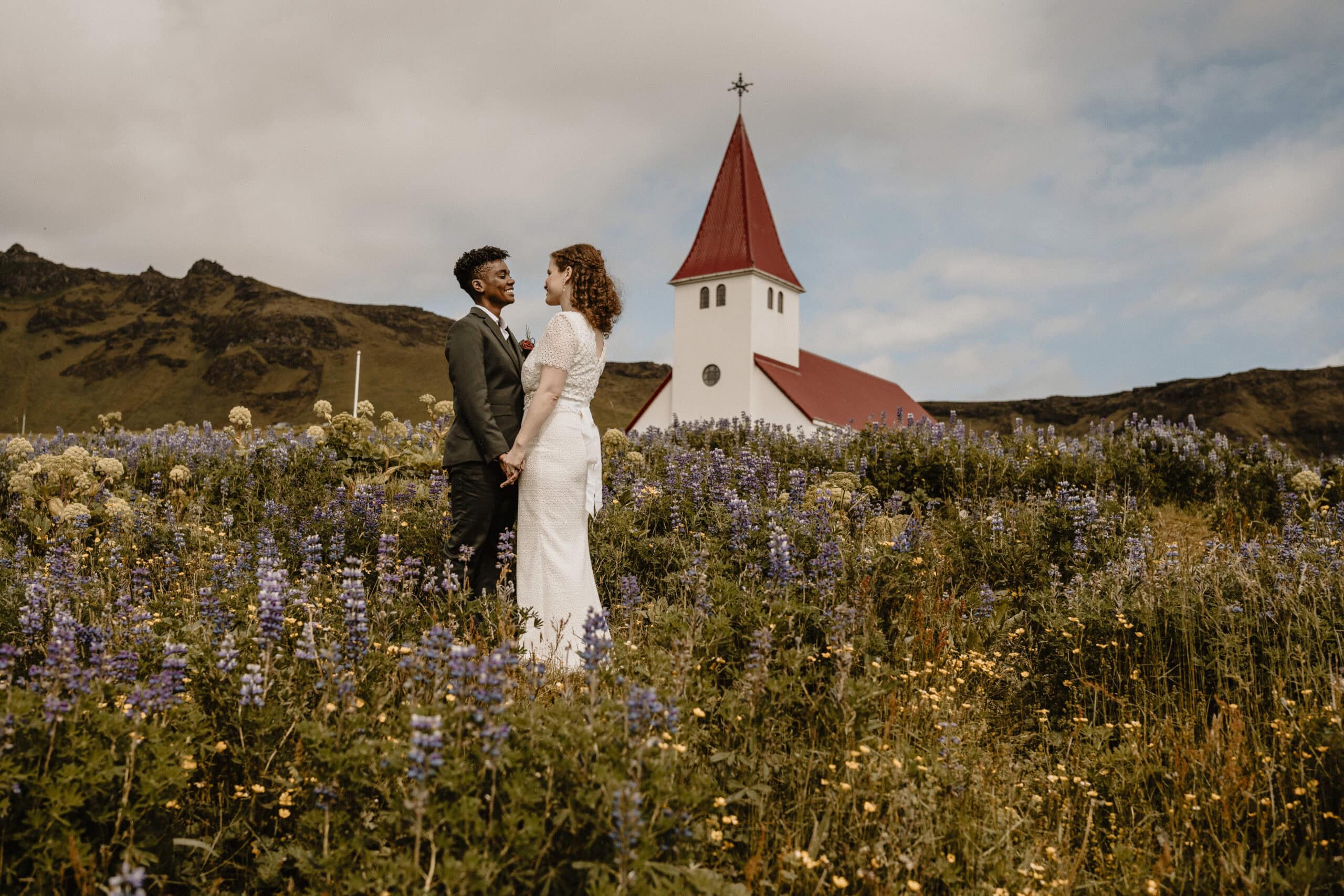 Romantic elopement of Zephyr & Luna in front of a church amid Icelandic wildflowers.
