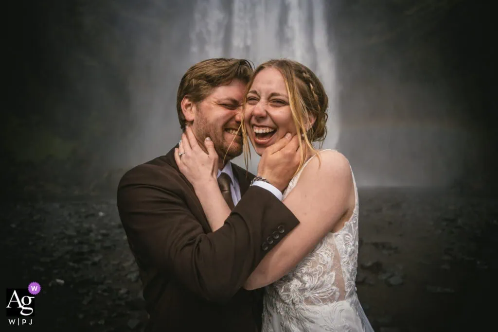 Happy couple at waterfall during Iceland elopement, celebrating love.
