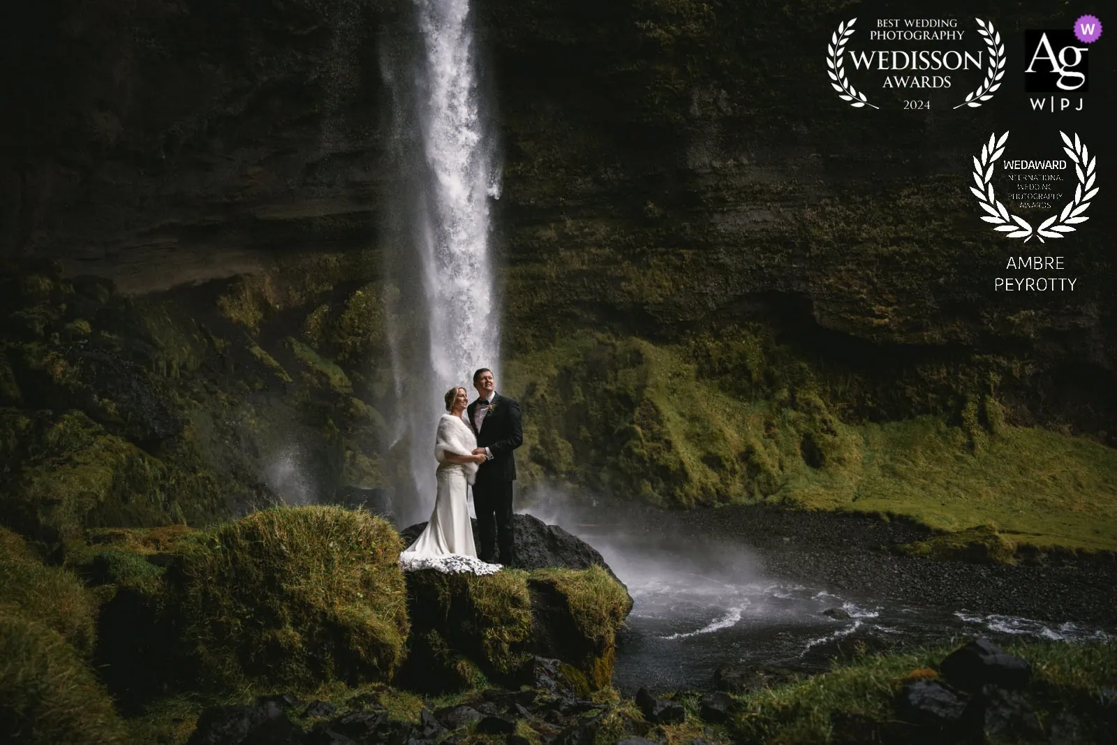 Elopement ceremony by a stunning Iceland waterfall with a couple in wedding attire.