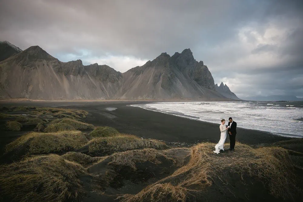 Elopement on Icelandic black sand beach with mountains in background.