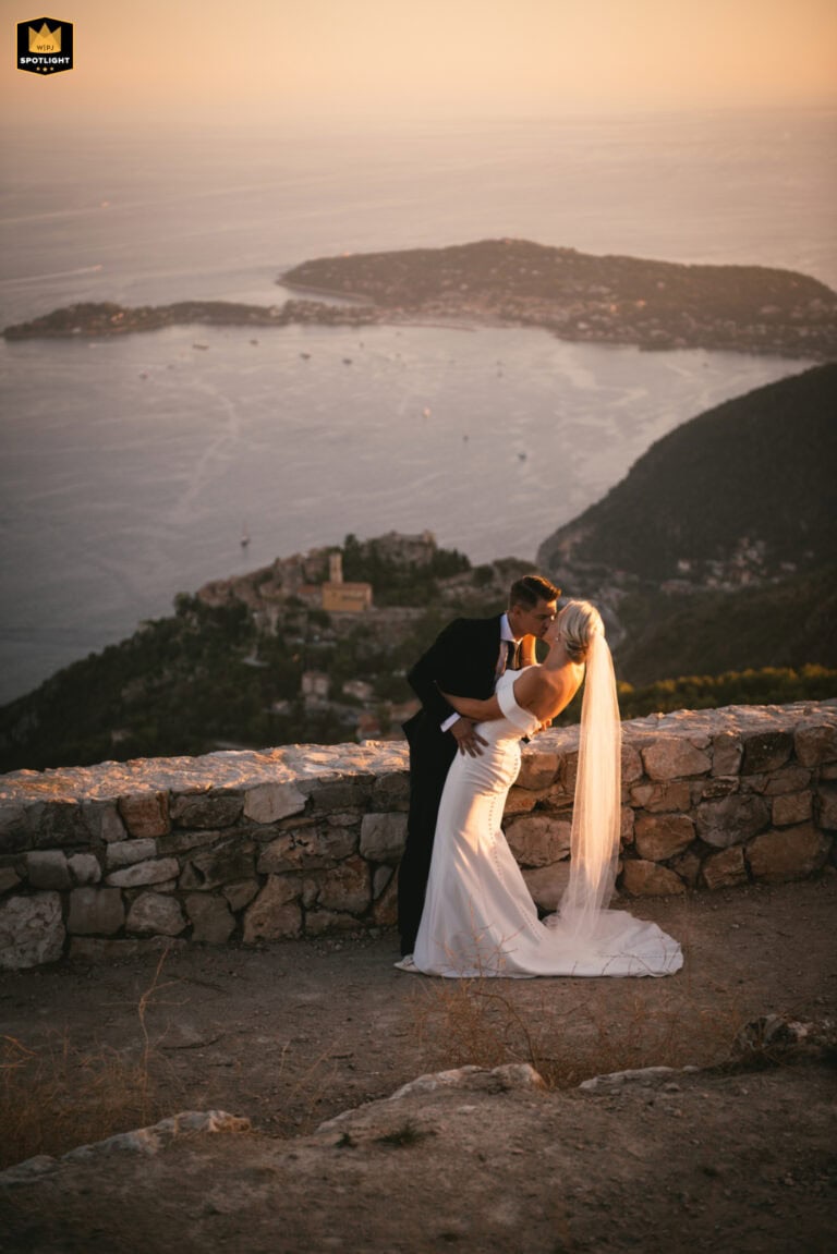 Elopement couple kissing with scenic Italian coastline in background.