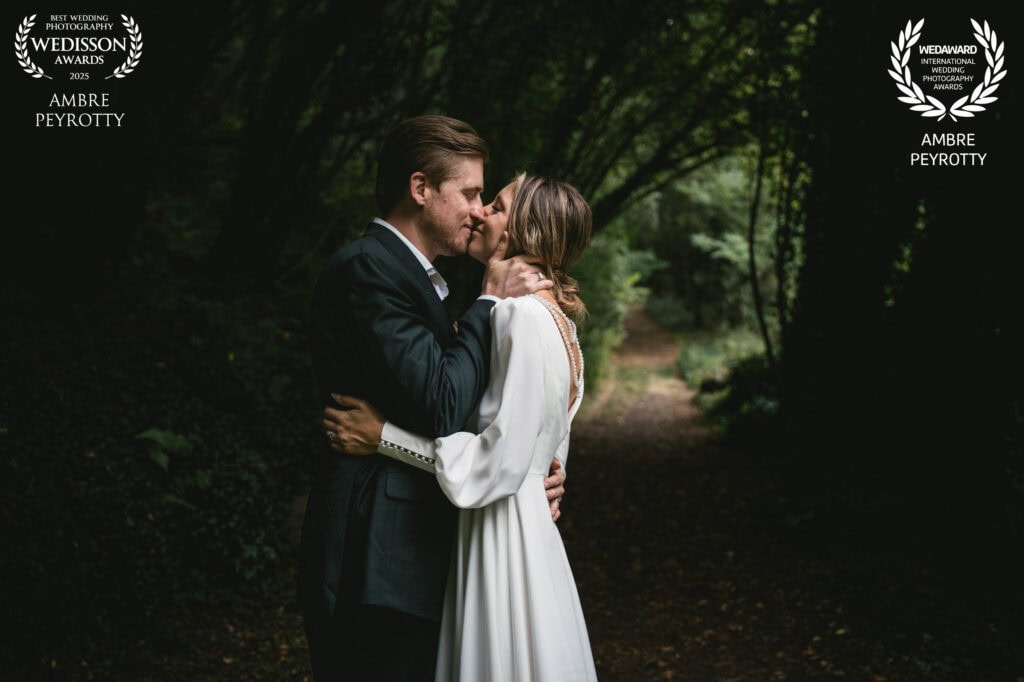 Romantic couple sharing a kiss during an elopement ceremony in a lush forest setting.