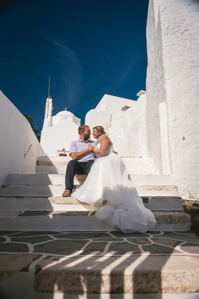 Elopement couple on white stairs with Greek architecture at sunset.