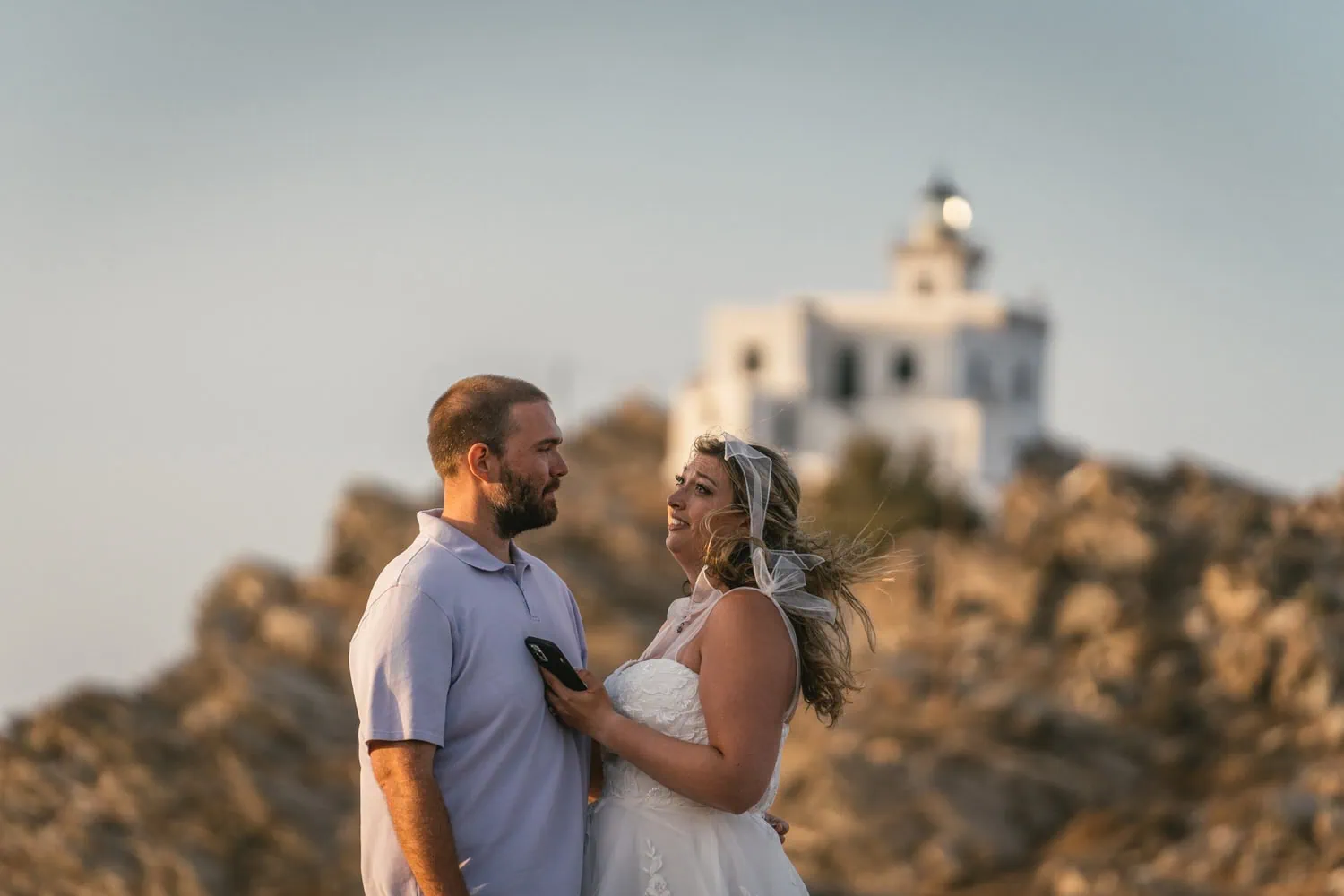 Romantic couple during sunset elopement on Paros, Greece with white chapel in background.