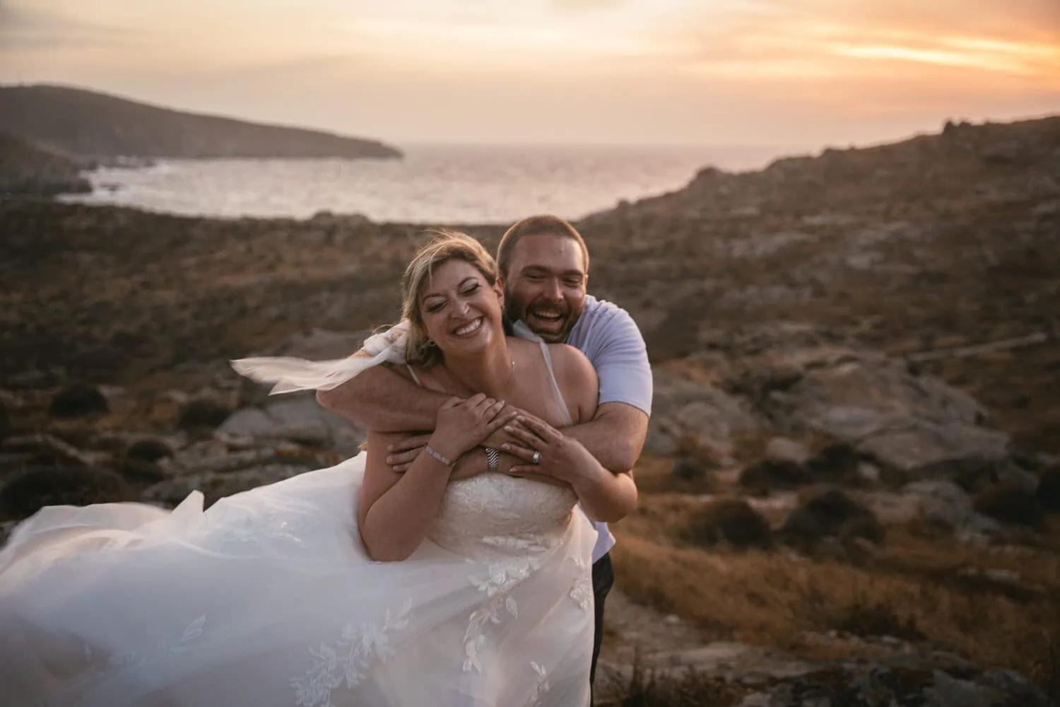 Happy couple embracing during sunset on Paros, Greece, celebrating their elopement.