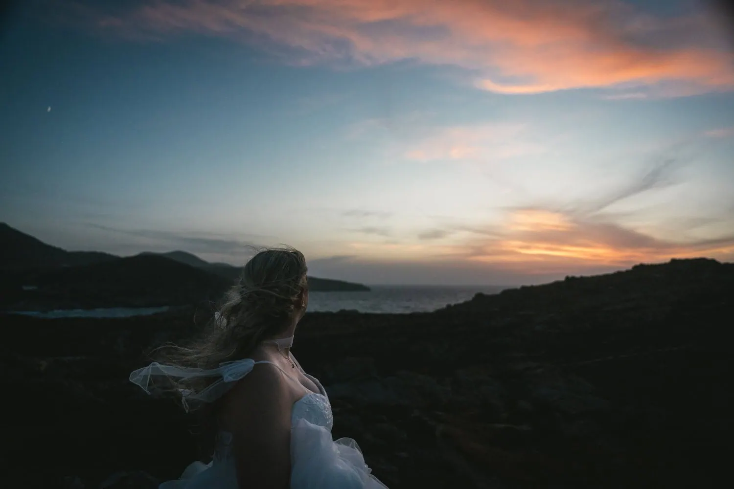 Elopement at sunset on the island of Paros, Greece, with a bride overlooking the ocean and dramatic.