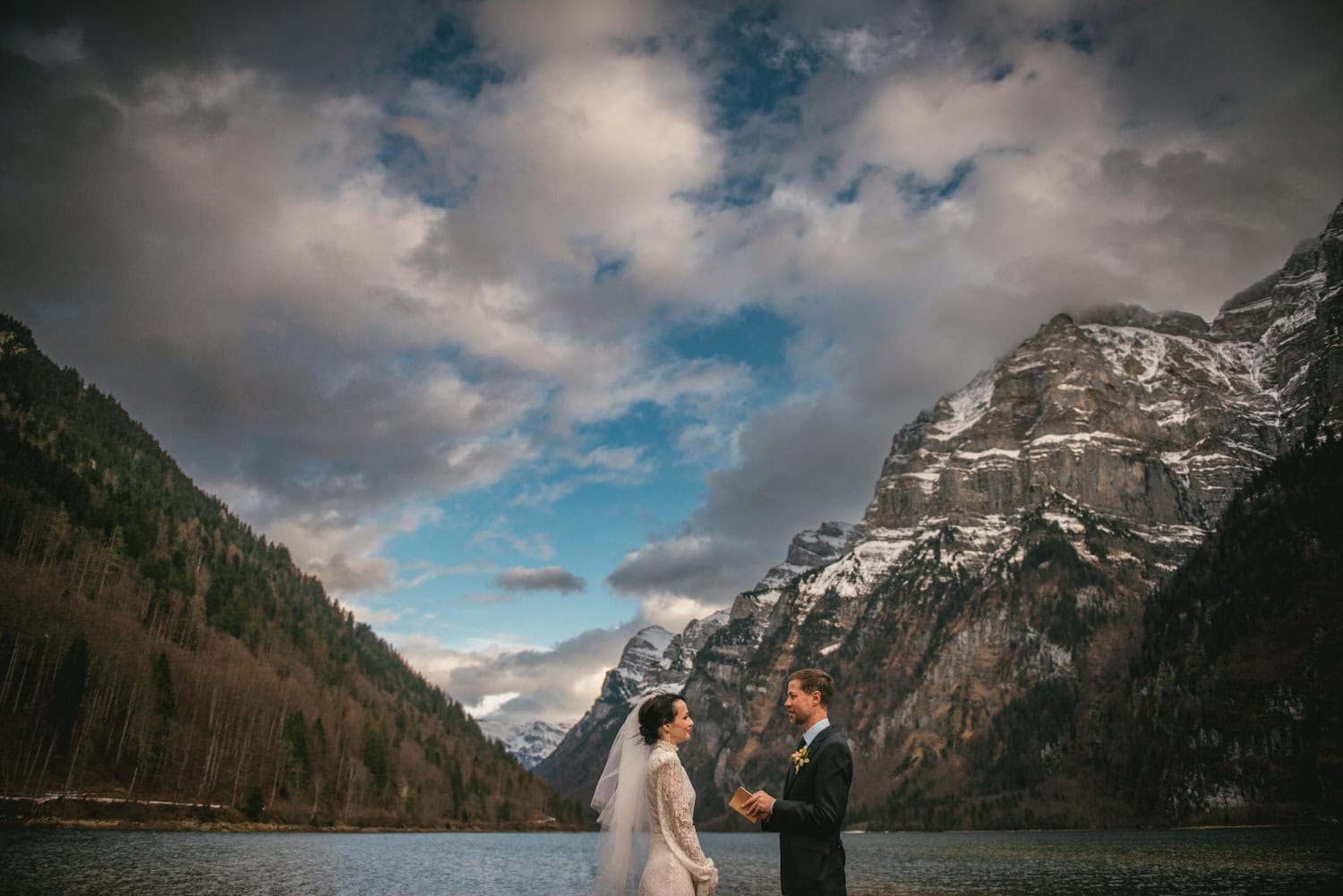 Elopement ceremony in stunning Swiss mountain landscape with bride and groom by a serene lake.