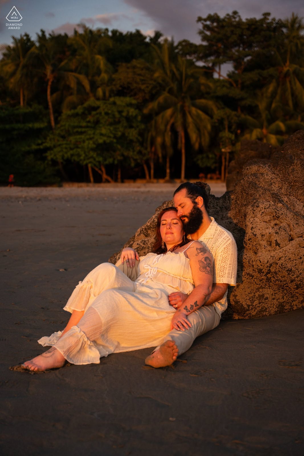Couple eloping barefoot on a deserted white sand beach in Fiji at golden hour