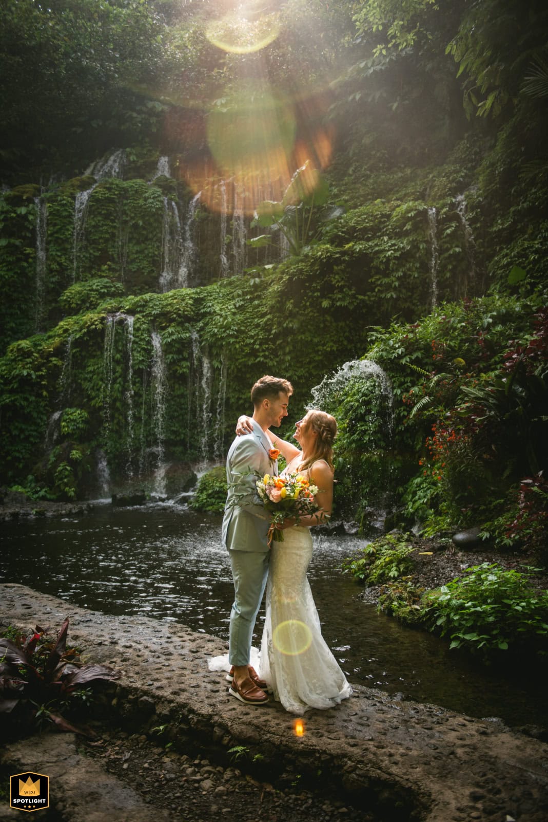 Barefoot couple in light elopement attire walking through shallow lagoon water in Fiji