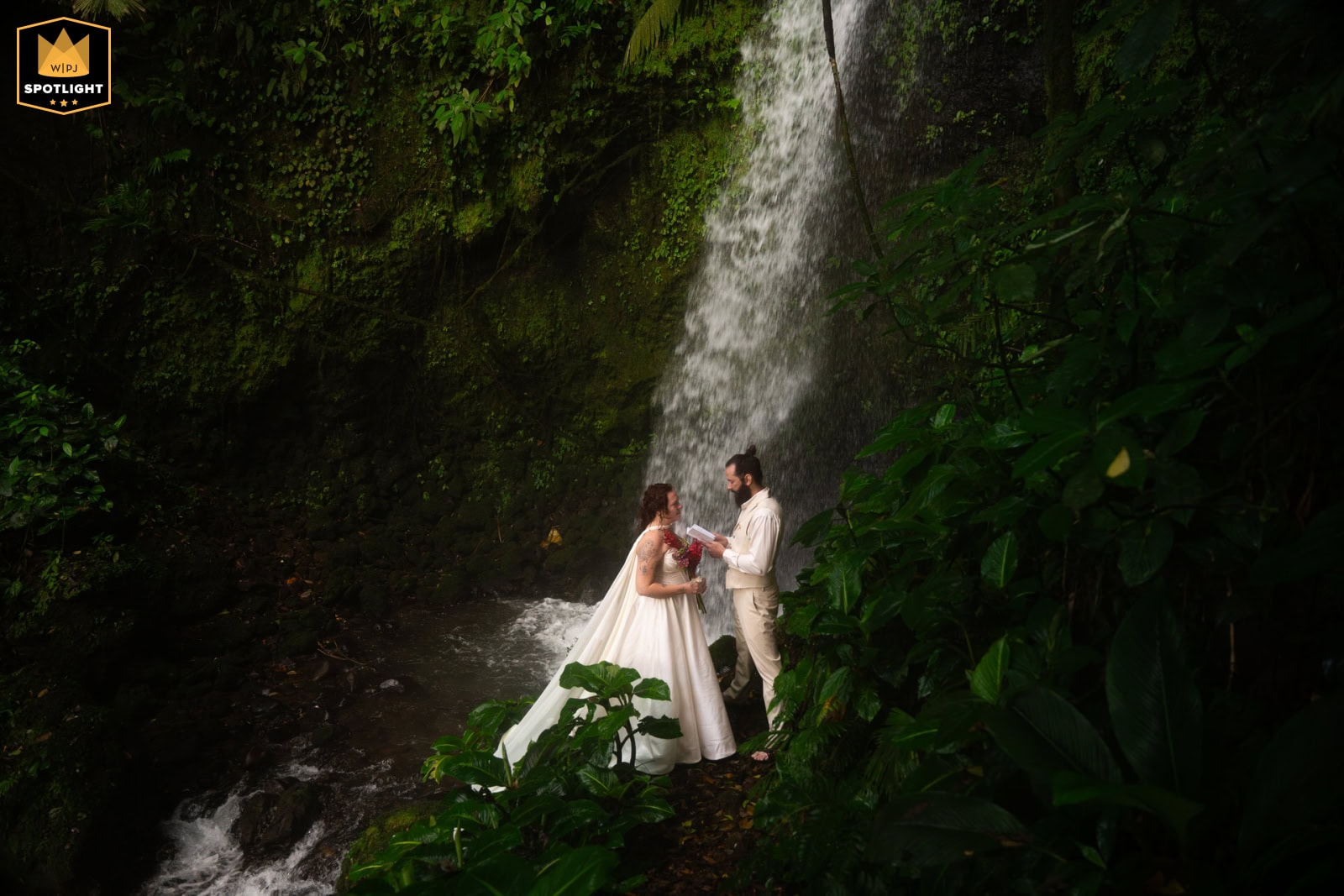 Newlyweds swimming in a jungle waterfall pool during their Fiji elopement adventure