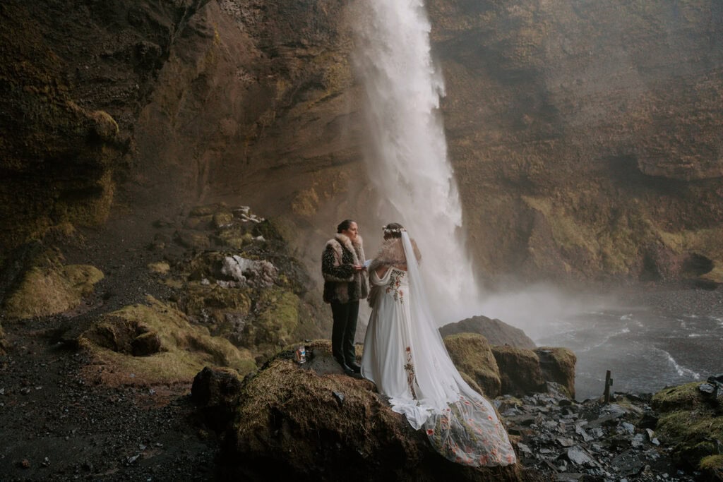Bride and groom at waterfall during elopement in nature setting.